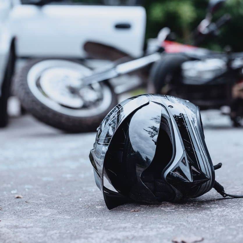Close up of a black motorcycle helmet on the street with overturned motorbike onthe background